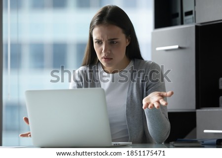 Unexpected trouble. Annoyed nervous millennial woman secretary employee office manager sitting by computer screen receiving email with bad news making critical mistake having problems with connection Royalty-Free Stock Photo #1851175471