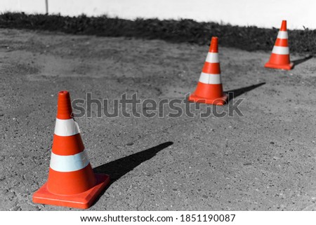 Traffic signal cone with white rings on old cracked asphalt. The background is blurred.