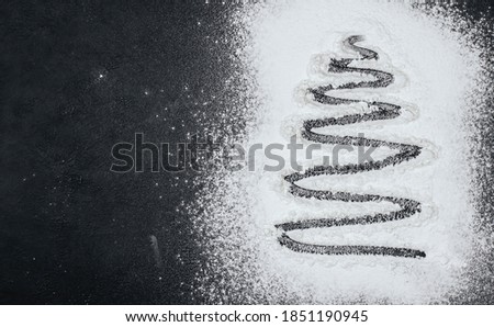 Silhouette of a Christmas tree on flour copy space. Flour for Christmas baking on a black background.