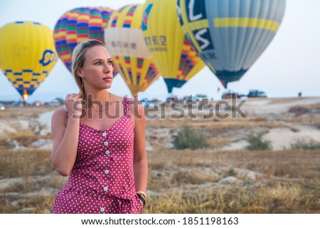 a girl is walking against the background of balloons in cappadocia
