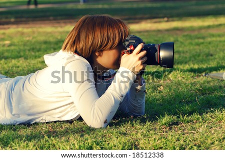 professional woman photographer in park on a grass.Cross effect