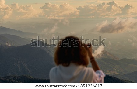 young woman photographer taking photo at mountain peak, selective focus on a background