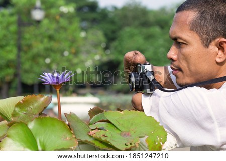 Portrait of a person using a camera for a lotus flower;People with disabilities are using a camera;Disabled person.