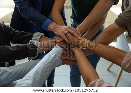 Stacking palms. Motivated business people employees corporate team members of different age and race putting hands together demonstrating unity bonding connection promising help support, close up view Royalty-Free Stock Photo #1851296752