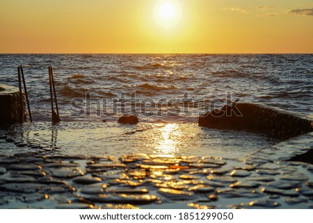 Sunset at sea. Rocky coast, splashing water. Waves crash on the shore.