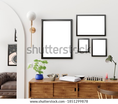 Stylish and eclectic dining room interior with mock up poster map, sharing table design chairs, gold pedant lamp and elegant sofa in second space. White walls, wooden parquet. Tropical leafs in vase. Royalty-Free Stock Photo #1851299878