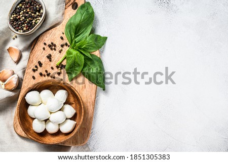 Mini mozzarella cheese in a wooden bowl with Basil leaves. gray background. Top view. Copy space
