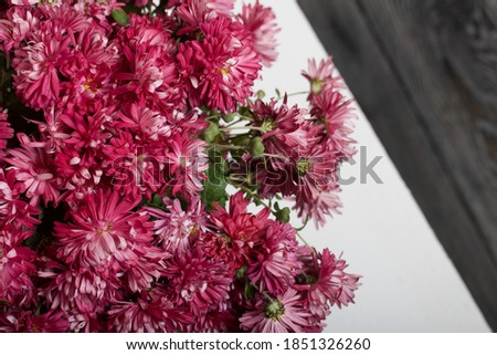 Bouquet of red chrysanthemums on a white table surface.