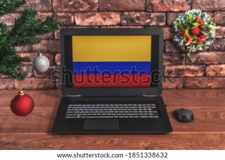 Christmas, new year's composition. Branches of the tree are decorated with Christmas balls on the background of a laptop with the image of the flag of Colombia