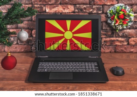 Christmas, new year's composition. Branches of the tree are decorated with Christmas balls on the background of a laptop with the image of the flag of Macedonia