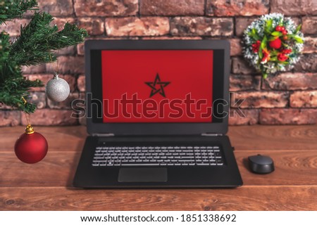 Christmas, new year's composition. Branches of the tree are decorated with Christmas balls on the background of a laptop with the image of the flag of Morocco