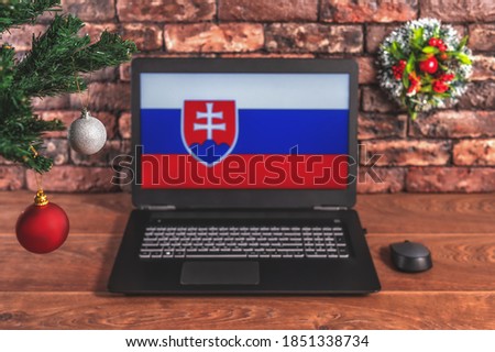 Christmas, new year's composition. Branches of the tree are decorated with Christmas balls on the background of a laptop with the image of the flag of Slovakia