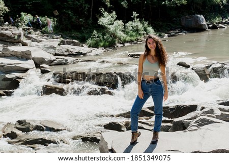 Waterfall in mountain river. Girl is travelling in Karpathian mountains and feeling freedom. Cascade waterfall and beautiful young woman