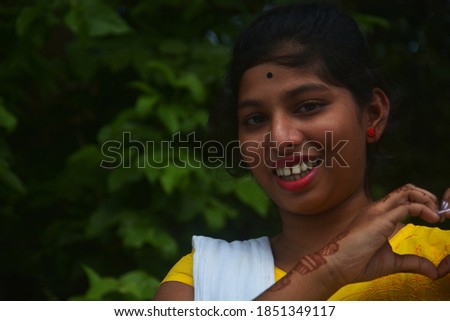 Close up of a teenage girl wearing yellow  salwar, earrings with long dark hair and bindi on forehead making love sign by hand, selective focusing