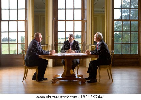 Three senior businessmen sitting at the table in their office and having a serious discussion about the business reports