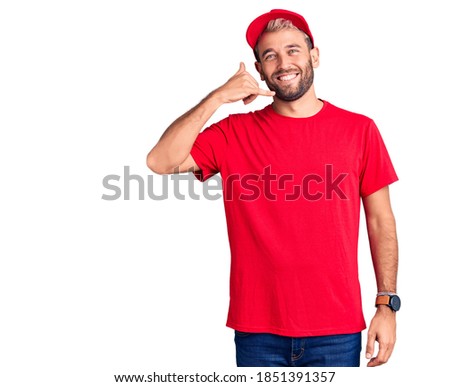 Young handsome blond man wearing t-shirt and cap smiling doing phone gesture with hand and fingers like talking on the telephone. communicating concepts. 