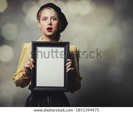 Beautiful girl in vintage clothes with photo frame on gray background