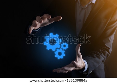 Business man in suit holding metal gears and cogwheels mechanism representing interaction teamwork concept,hand hold group of virtual cog gears wheel.