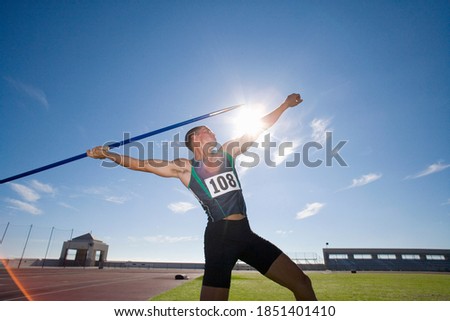Young male athlete preparing to throw a javelin during a practice session at the track on a bright, sunny day Royalty-Free Stock Photo #1851401410