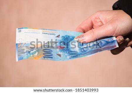 World money concept, close up of 100 swiss franc banknote, photo of CHF currency isolated. Hand holding money or giving swiss franc.