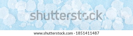 White round plastic foam sheet pieces on blue background. Winter snowfall concept. Torn foam polyethylene transparent pieces as snowflakes.