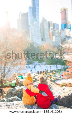 Adorable little girls background of ice-rink in Central Park at New York City