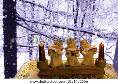 Choir of small Golden angels with burning candles on the background of winter snow-covered trees.