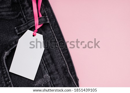Empty paper price tag on black denim pants close-up. Place for text, Black Friday Sale template