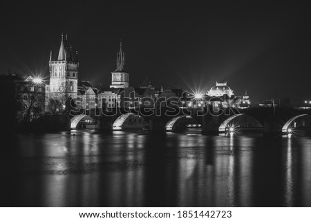 Evening panorama of Prague, Czech Republic. Black and white photo. Charles Bridge (Karluv most) reflected in Vltava River. Long exposure city lights.Amazing European cityscape.Travel urban concept