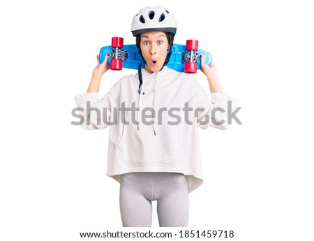 Beautiful brunette young woman wearing safety helmet and skate scared and amazed with open mouth for surprise, disbelief face 