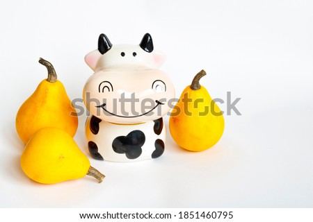 Three orange pumpkins in the shape of a pear and a piggy Bank in the shape of a cow are white and black on a white background. Crop, farm. Hello autumn