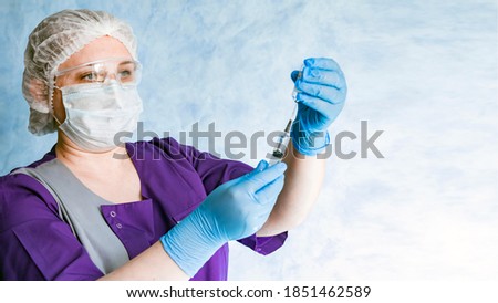 Blue-eyed nurse in overalls and personal protective equipment on a blue background. Close-up. Panorama. Place for an inscription.