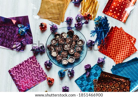 Top view of plate full of chocolates with gift paper and wrapped chocolates in background. Holiday gift concept