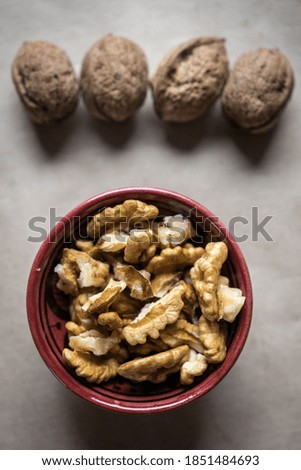 Chopped walnuts in a bowl, whole nuts in the background. Nuts in a bowl. Beautiful photo of nuts.