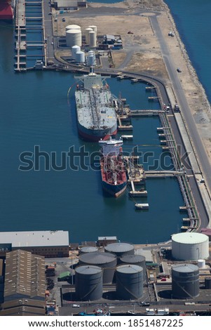 Vertical shot of the aerial view of a large oil tanker moored at a commercial dock.