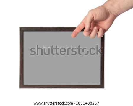 Hand holding a photo frame. Objects on a white isolated background. Place the text on a gray  sheet. Hand of man. Holding on to the frame. The grey leaf is framed by a wooden frame.