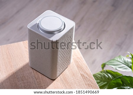 electronic equipment smart speaker on the table in the room and houseplant,  smart speaker. gadget in the apartment close-up, selective focus, tinted image, bright sunlight from the window