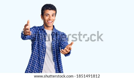 Young african amercian man wearing casual clothes smiling cheerful offering hands giving assistance and acceptance. 