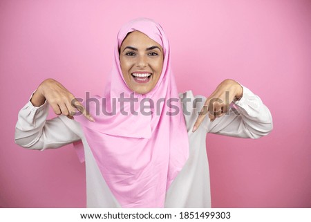 Young beautiful arab woman wearing islamic hijab over isolated pink background looking confident with smile on face, pointing oneself with fingers proud and happy.
