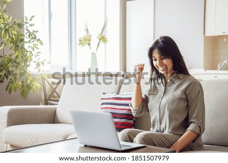Happy indian woman student, winner celebrating achievement, online bid win, victory, success raising hand in yes gesture looking at laptop feeling glad receiving discount voucher on email at home. Royalty-Free Stock Photo #1851507979