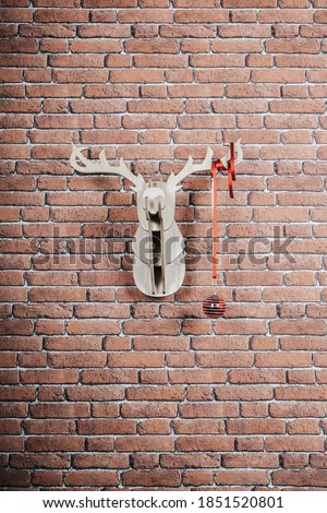 Wooden deer hanging on the wall decorated with garlands and christmas ball. Vertical picture