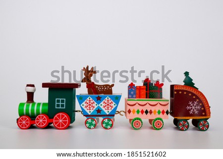 A toy wooden Christmas train carries the attributes of winter holidays on a white background. Image for a decorative Christmas holiday concept. Free space to copy