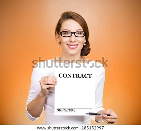 Closeup portrait smiling, young business woman with glasses, holding contract pointing with pen at space for signature isolated orange background. Positive face expression emotion, attitude perception