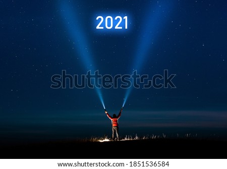  New year 2021. Success new year concept. Milky Way.Long exposure photography, a
man holding a flashlight and illuminating the sky full of stars with 2021 inscription. 