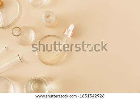 Laboratory glassware and pipette with serum and oil on beige background. Natural medicine, cosmetic research, bio science, organic skin care products. Concept skincare. Dermatology.Flat lay, top view. Royalty-Free Stock Photo #1851542926