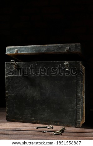 Vertical image.Opened wooden chest and vintage keys on the aged surface against dark background