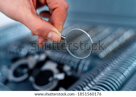 Hand changes lenses of trial frame phoropter. Lenses from set of corrective frame. Eye test glasses set. Ophthalmology concept. Royalty-Free Stock Photo #1851560176