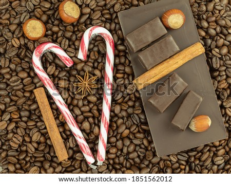 Coffee beans and chocolates as a background with place for text. Coffee with chocolate and cinnamon with nuts. Chocolates on coffee beans