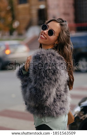 Lovable charming girl walking in the city dressed fashionable outfit with happy emotions