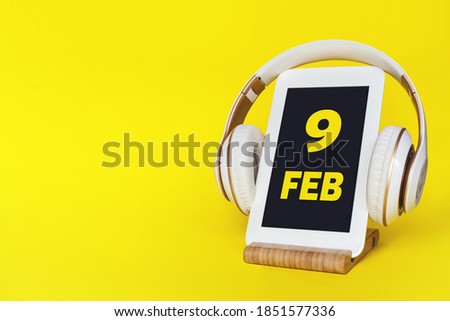 February 9th. Day 9 of month, Calendar date. Stylish headphones and modern tablet on yellow background. Space for text. Education, technology, lifestyle. Winter month, day of the year concept